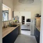 Cuisine double linéaire à l’Anse à l’Âne : façades bleu roi, plan de travail compact et agencement pensé pour la location saisonnière.