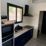 Cuisine double linéaire à l’Anse à l’Âne : façades bleu roi, plan de travail compact et agencement pensé pour la location saisonnière.