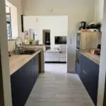 Cuisine double linéaire à l’Anse à l’Âne : façades bleu roi, plan de travail compact et agencement pensé pour la location saisonnière.