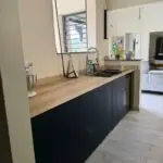 Cuisine double linéaire à l’Anse à l’Âne : façades bleu roi, plan de travail compact et agencement pensé pour la location saisonnière.