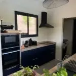 Cuisine double linéaire à l’Anse à l’Âne : façades bleu roi, plan de travail compact et agencement pensé pour la location saisonnière.