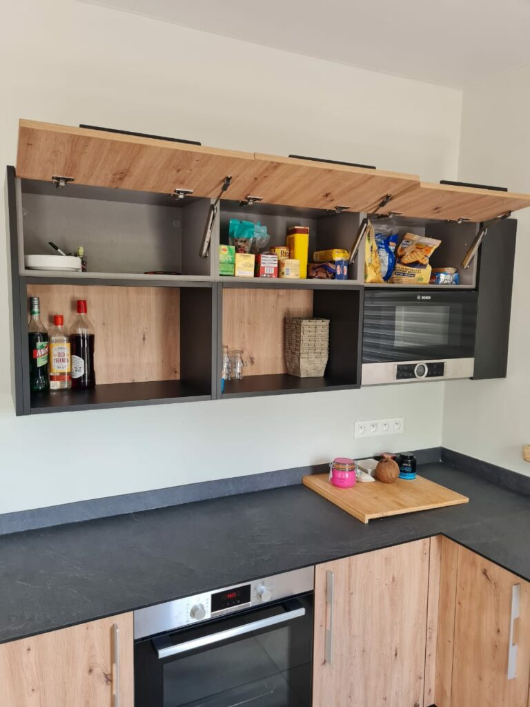 Cuisine sur mesure en Martinique avec façades effet chêne naturel, meubles hauts à ouverture relevable, plan de travail anthracite et four encastré Bosch