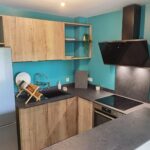 Cuisine sur mesure au Lamentin avec façades bois, évier noir et hotte inclinée