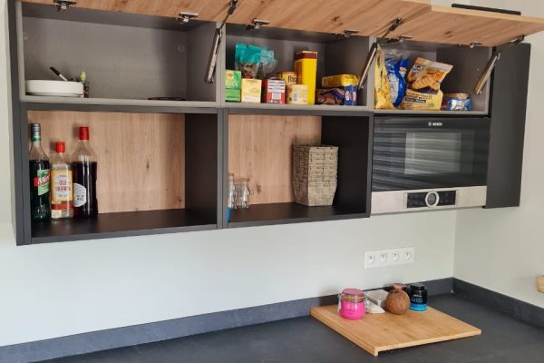 Cuisine sur mesure en Martinique avec façades effet chêne naturel, meubles hauts à ouverture relevable, plan de travail anthracite et four encastré Bosch